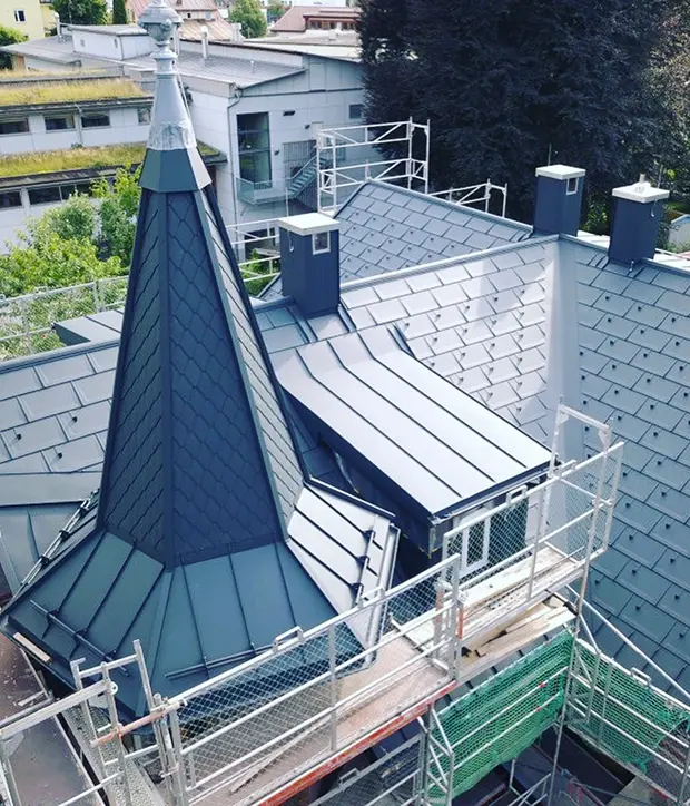 Dach- und Fassadenarbeiten aus Metall an Gebäude mit Turm und Gerüst